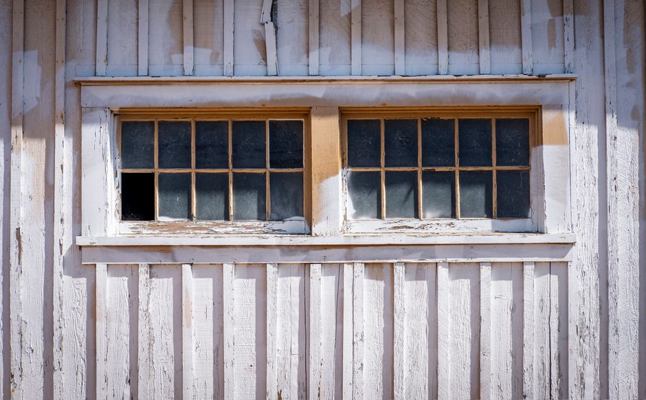 Close-up of a vintage wooden window on a rustic building facade with peeling paint.